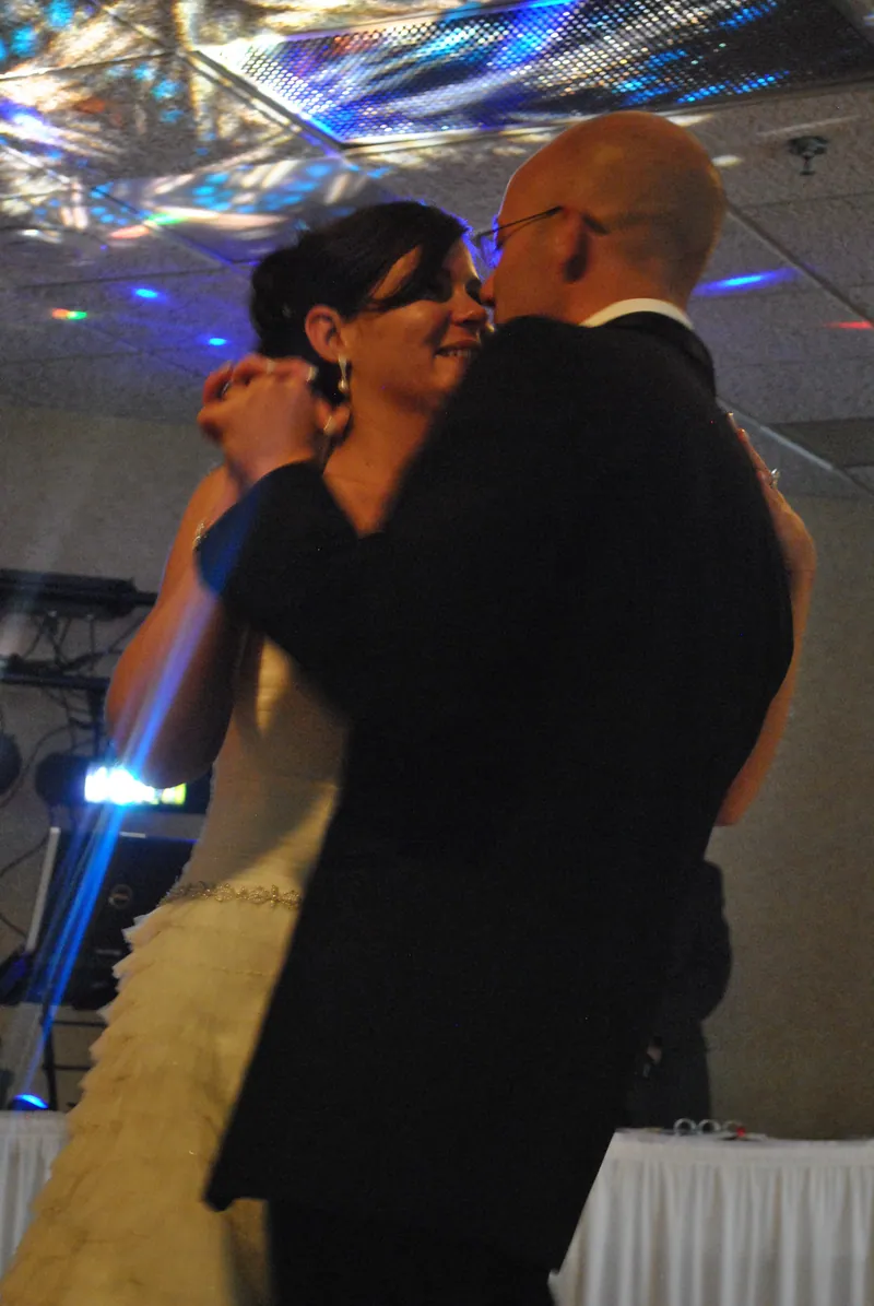 Angela and Jeremiah dance together under colored light reflected across the ceiling.