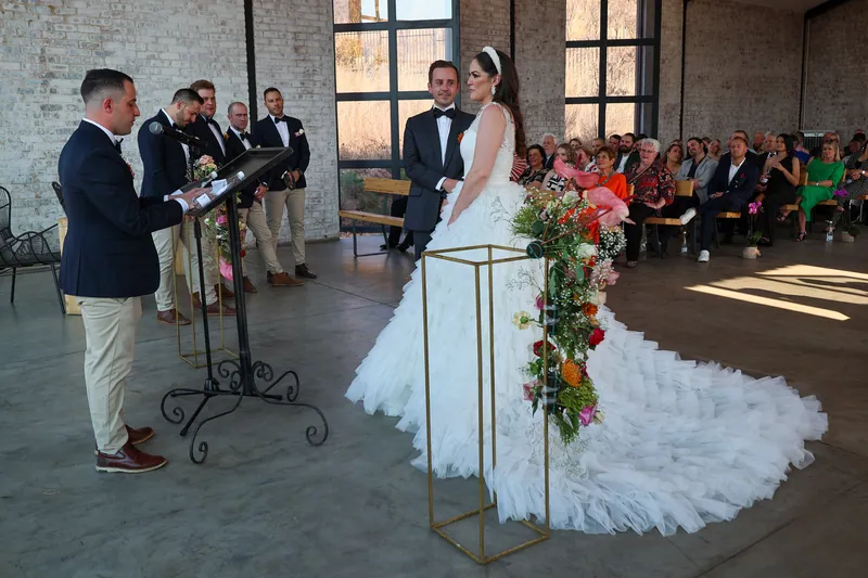 Pink and coral flowers trail over a slim gold-colored stand beside the couple during their ceremony.