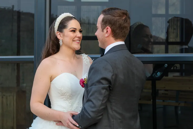 Roxy and Matthew face each other beside a dark window, her pearl-like headband reflected in the glass.